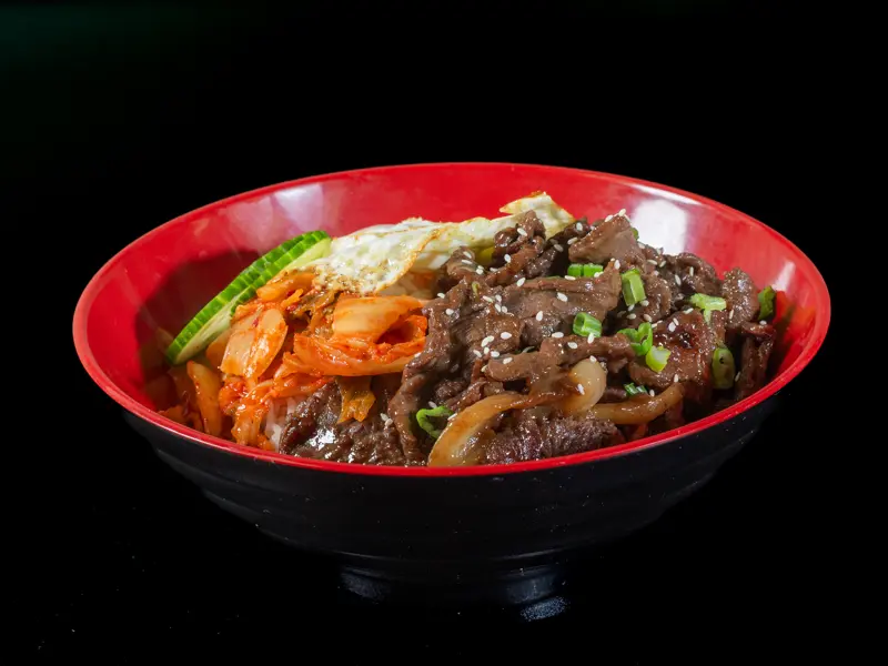 Korean beef bulgogi rice bowl with kimchi, cucumber and a fried egg