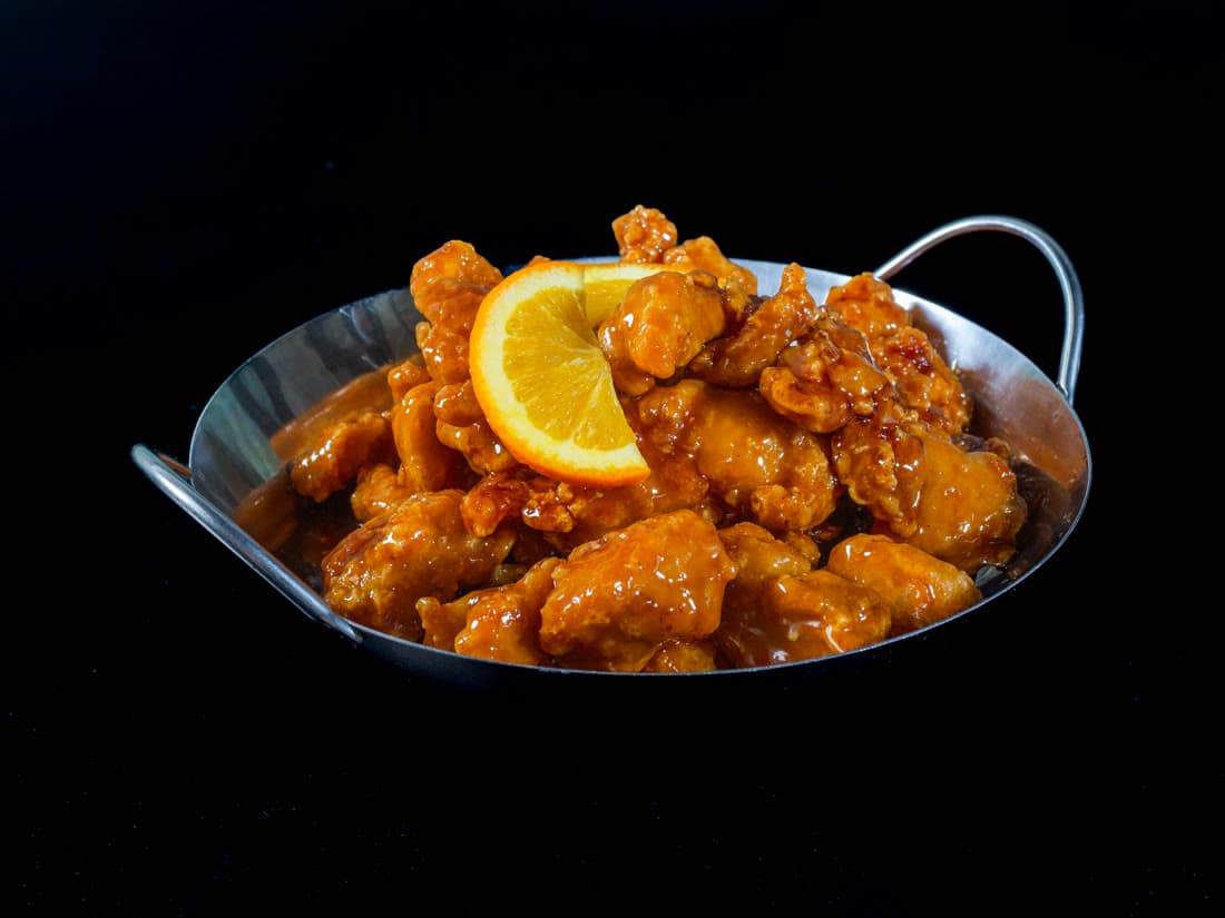 Orange chicken glazed and served in a steel wok at Bamboo House Express