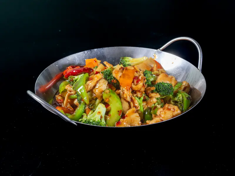 Szechuan chicken with peanuts, broccoli and chili in a steel wok